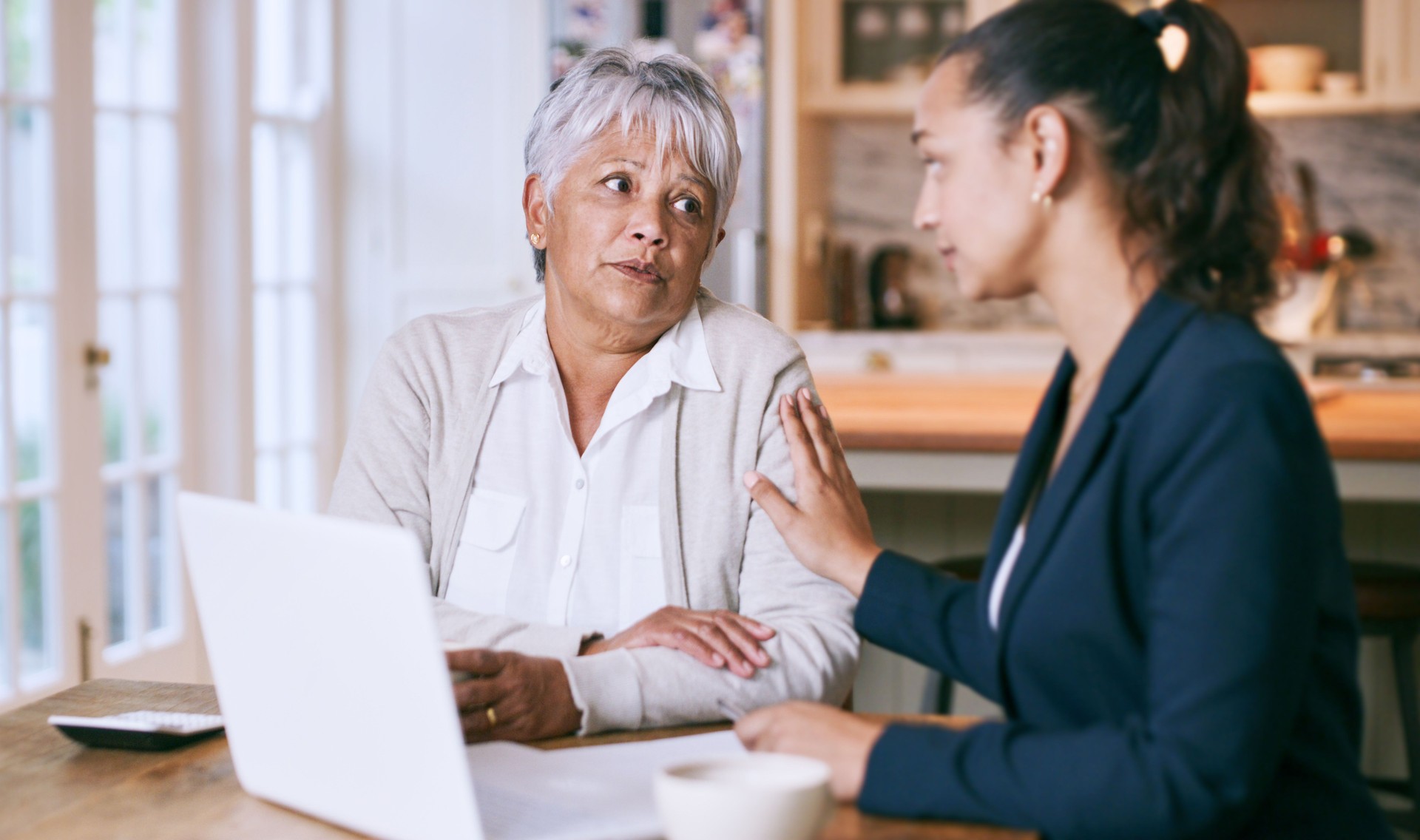 Shot of a senior woman using a laptop during a meeting with a consultant at home